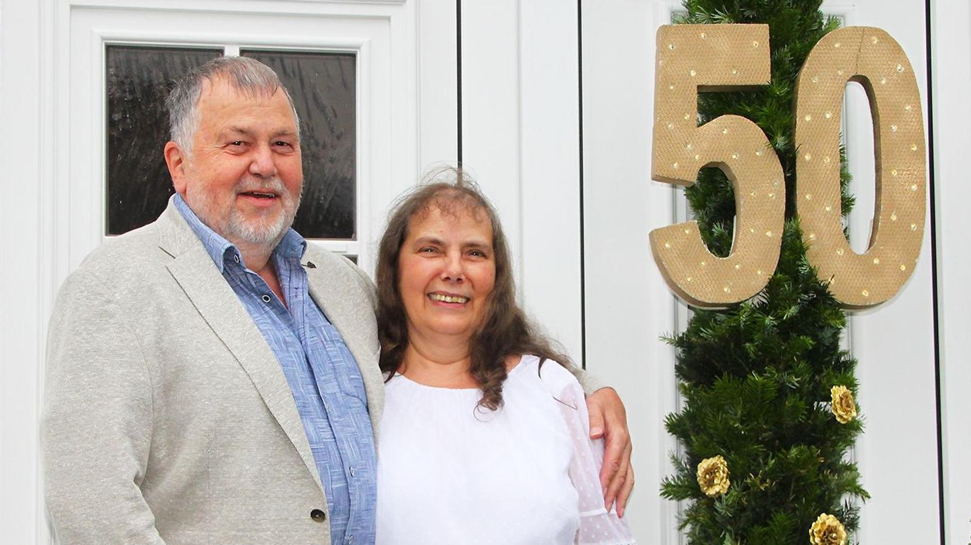 Das Jubelpaar Hans-Werner und Roswitha Schreiber vor der mit einem großen Kranz geschmückten Haustür mit einer großen 50.