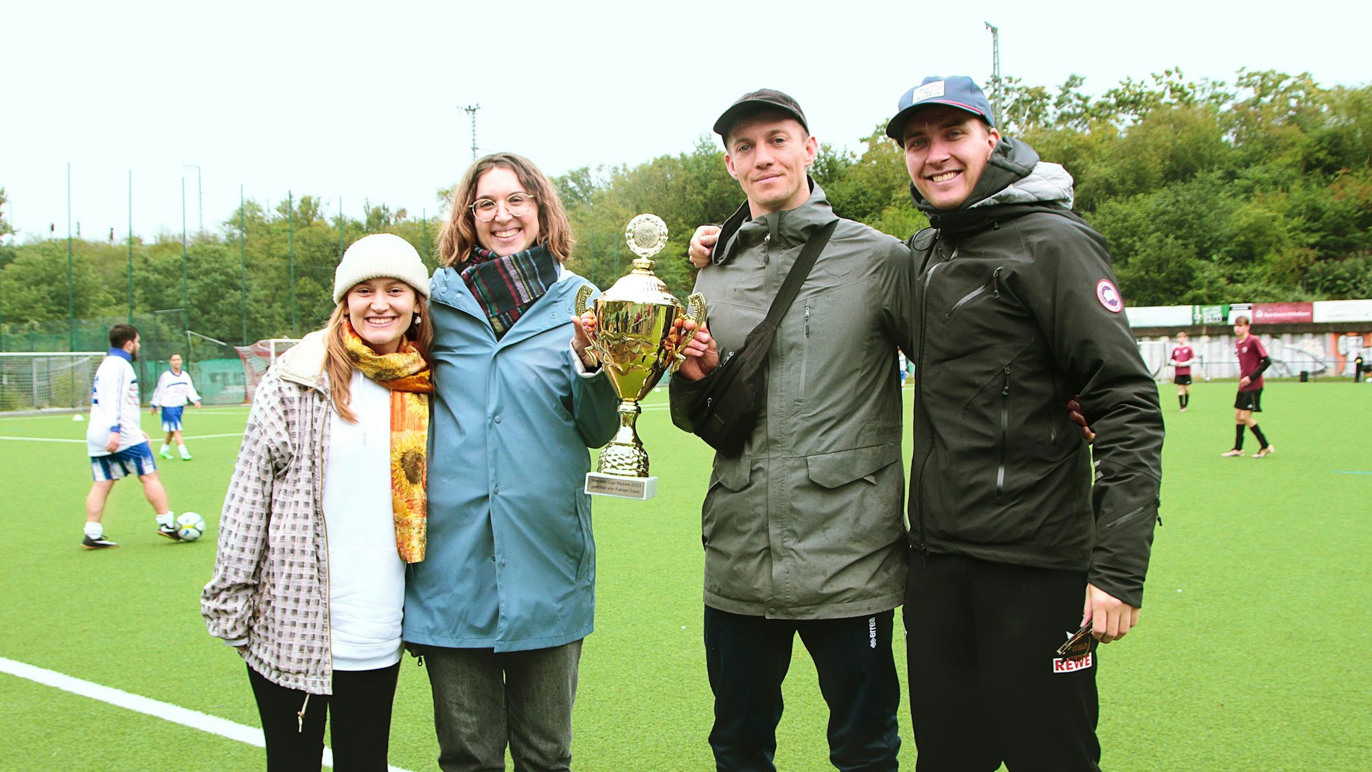 Das Rheinflanke-Organisationsteam des „Nippes-Veedelscup 2023“ (von links): Valerija Braun, Lena Fröhlich, Niklas Hack und Linus Funk mit dem Pokal in Gedenken an Fabian S.