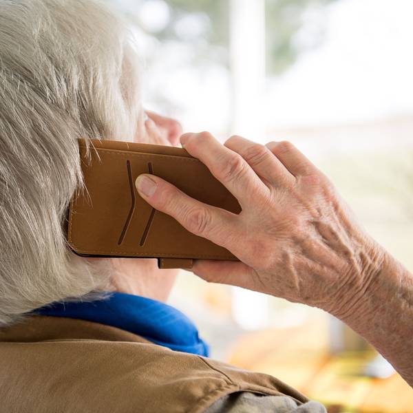 Das Foto zeigt eine Frau, die ein Telefon ans Ohr hält.