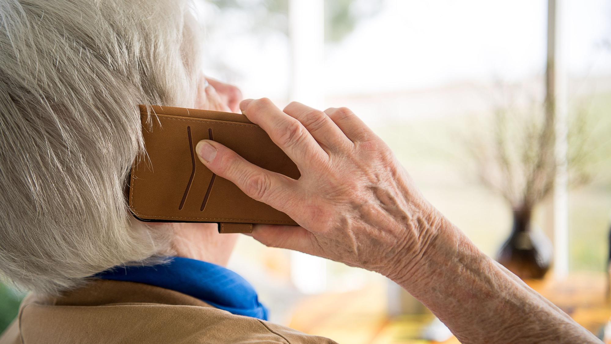 Das Foto zeigt eine Frau, die ein Telefon ans Ohr hält.
