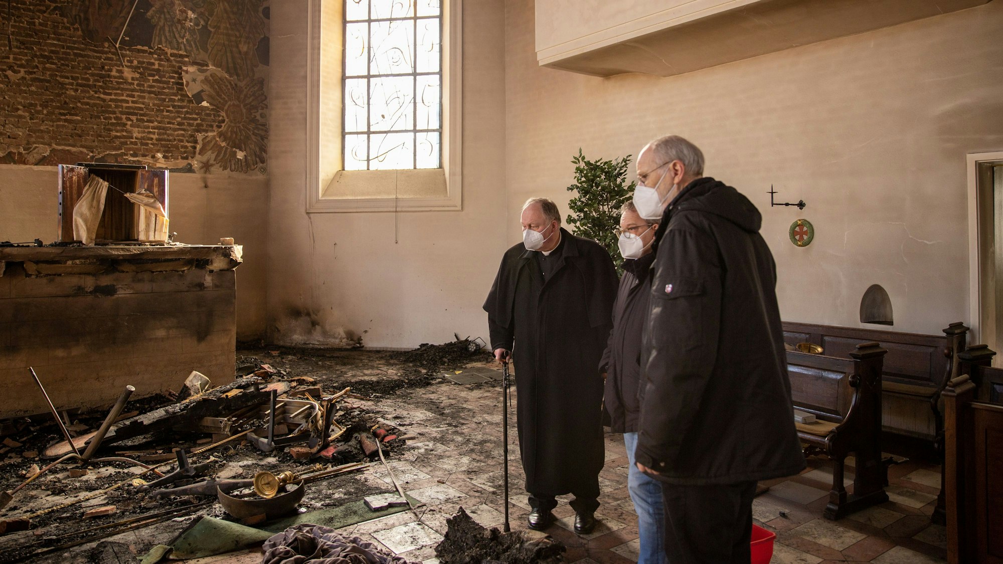 Drei Männer stehen in der durch ein Feuer völlig zerstörten Pfarrkirche Kreuzerhöhung in Wissen an der Sieg.