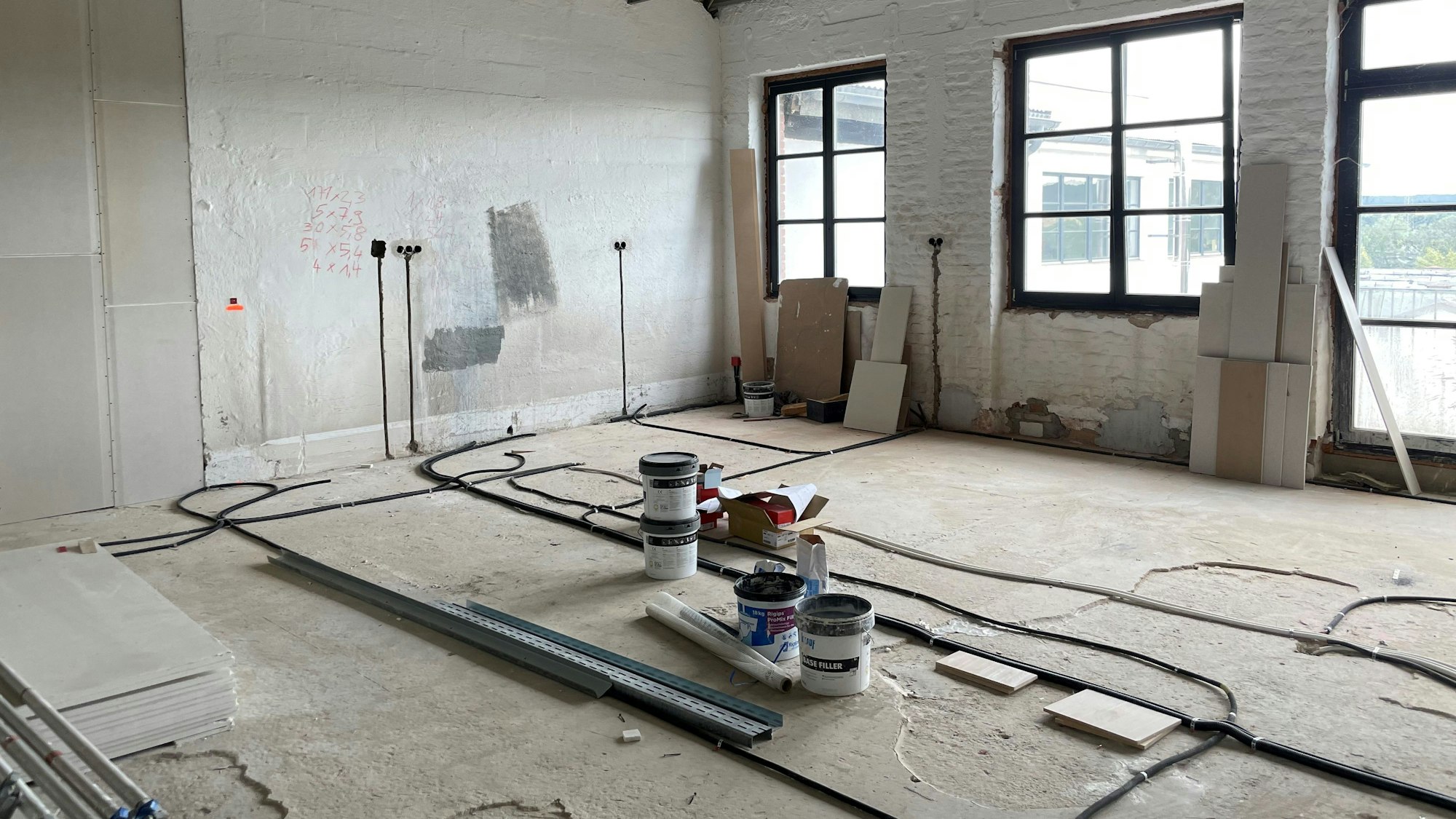 Das Bild zeigt einen Blick in einen Raum in der Alten Tuchfabrik in Euskirchen, der sich im Rohbauzustand befindet. Einige Bauutensilien stehen auf dem Boden.
