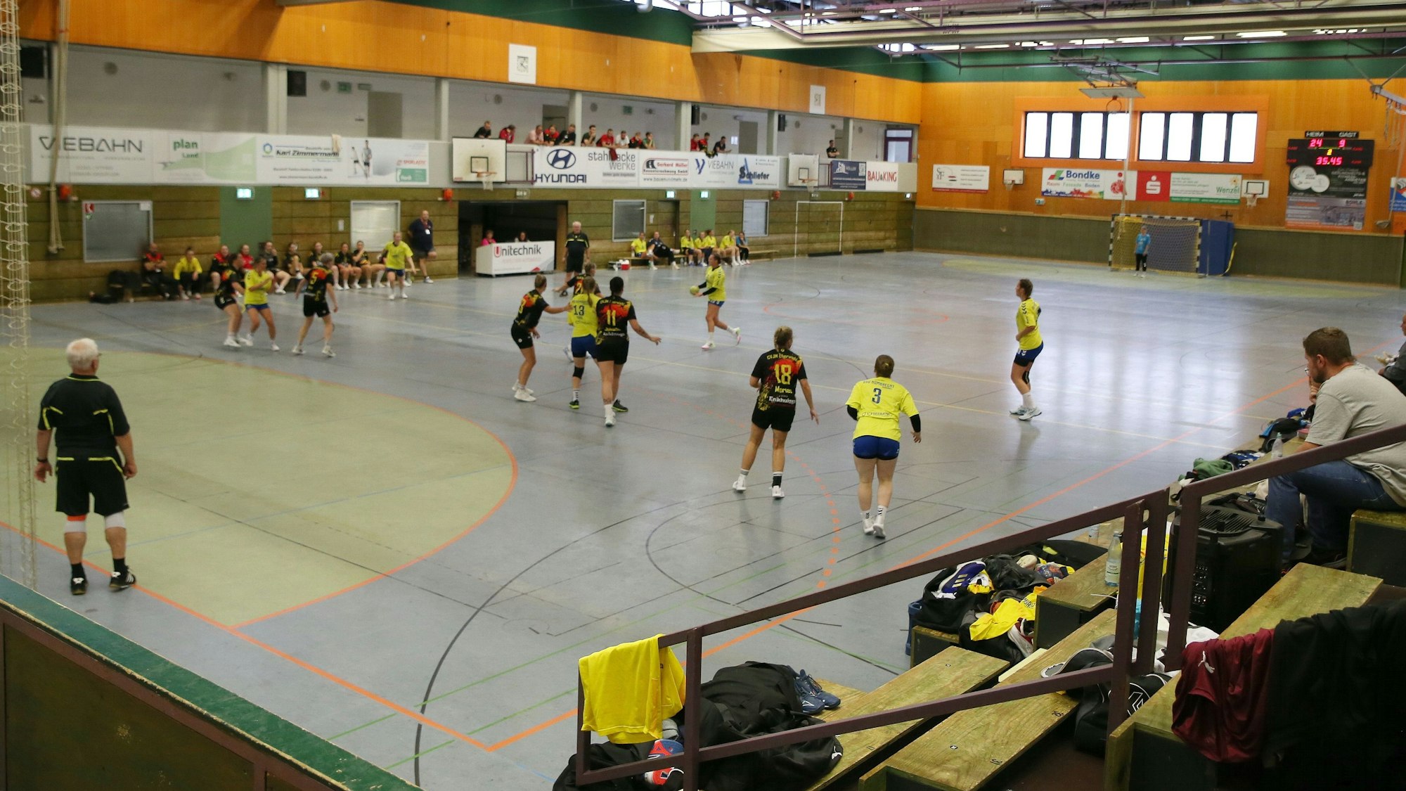 Auf einem Handballfeld in einer älteren Sporthalle läuft ein Handballspiel.