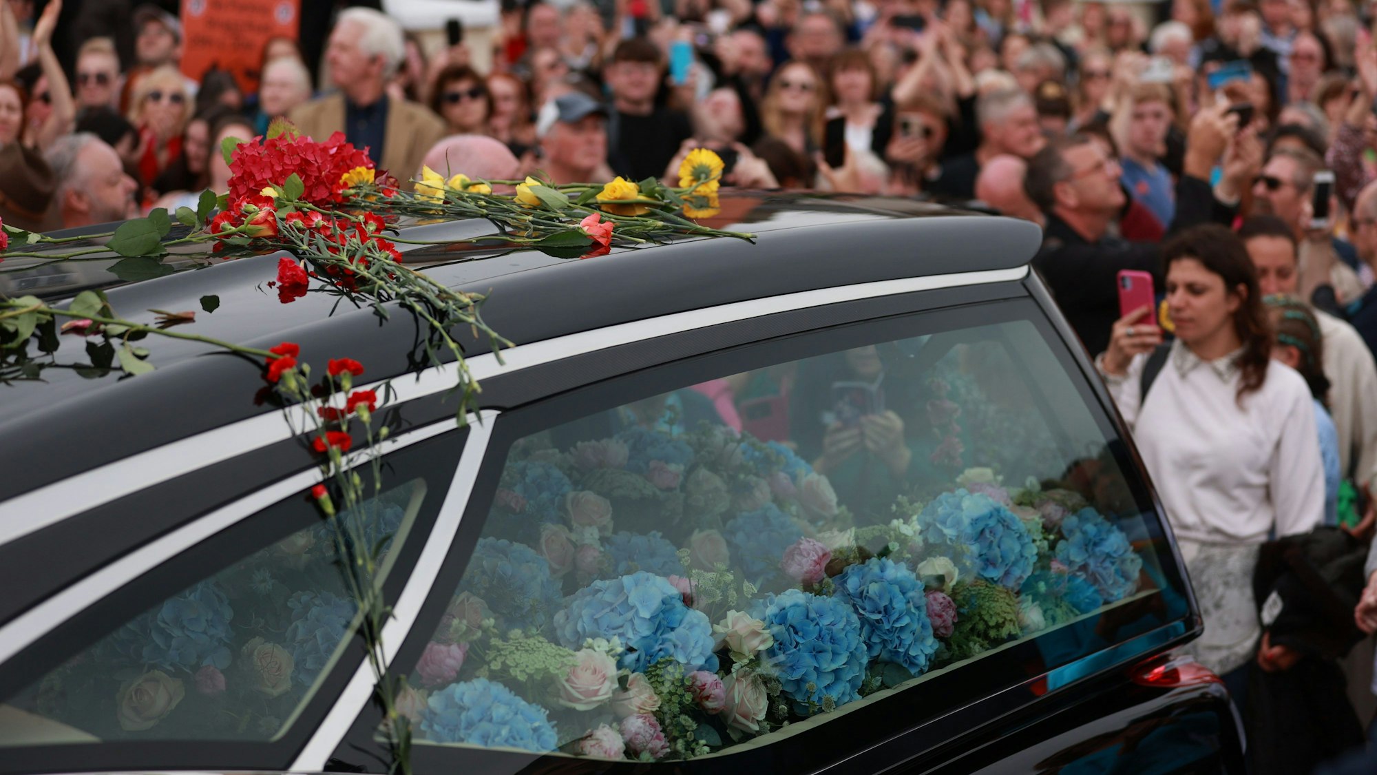 Fans der Sängerin Sinead O'Connor säumen eine Straße, um sich ein letztes Mal von der irischen Sängerin zu verabschieden, als ihr Trauerzug vor der privaten Trauerfeier durch ihre frühere Heimatstadt fährt.