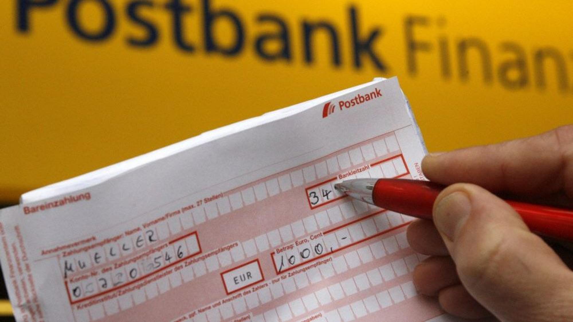 ILLUSTRATION - Ein Postbankkunde füllt einen Überweisungsträger aus.