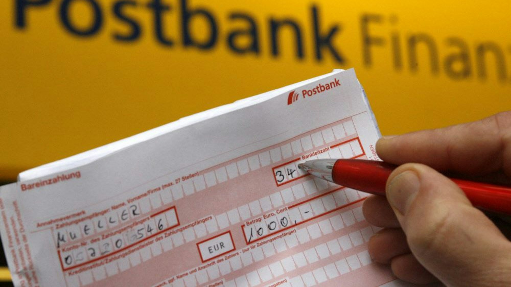 ILLUSTRATION - Ein Postbankkunde füllt einen Überweisungsträger aus.