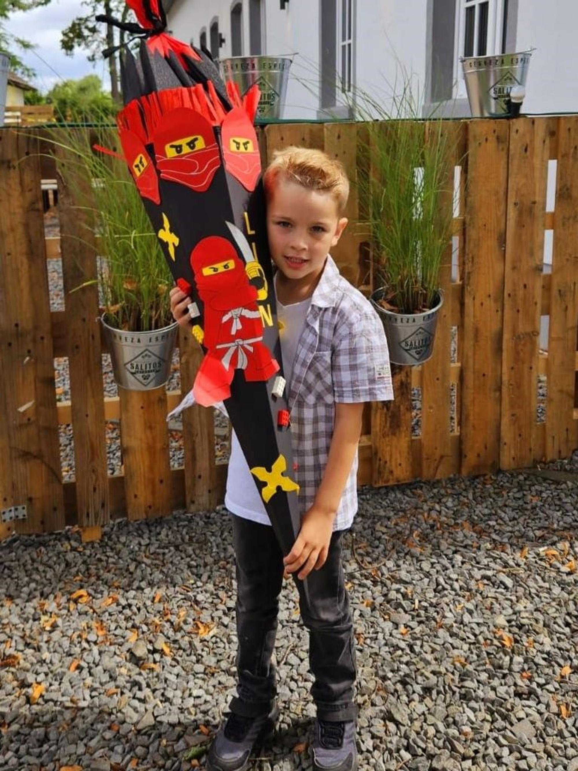 Das Bild zeigt den Sechsjährigen mit seiner schwarz-roten Schultüte.
