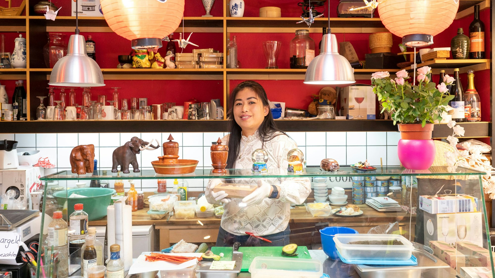 Blick in den Obst- und Gemüsehandel Banlao in Köln-Mühlheim, eine Frau lächelt hinter einem Tresen.