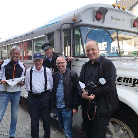 Menschen stehen an einem historischen amerikanischen Schulbus.