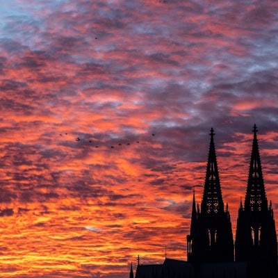 Die Silhouette des Kölner Doms vor einem Sonnenuntergang. Der Himmel ist rot und orange gefärbt. (Symbolbild)