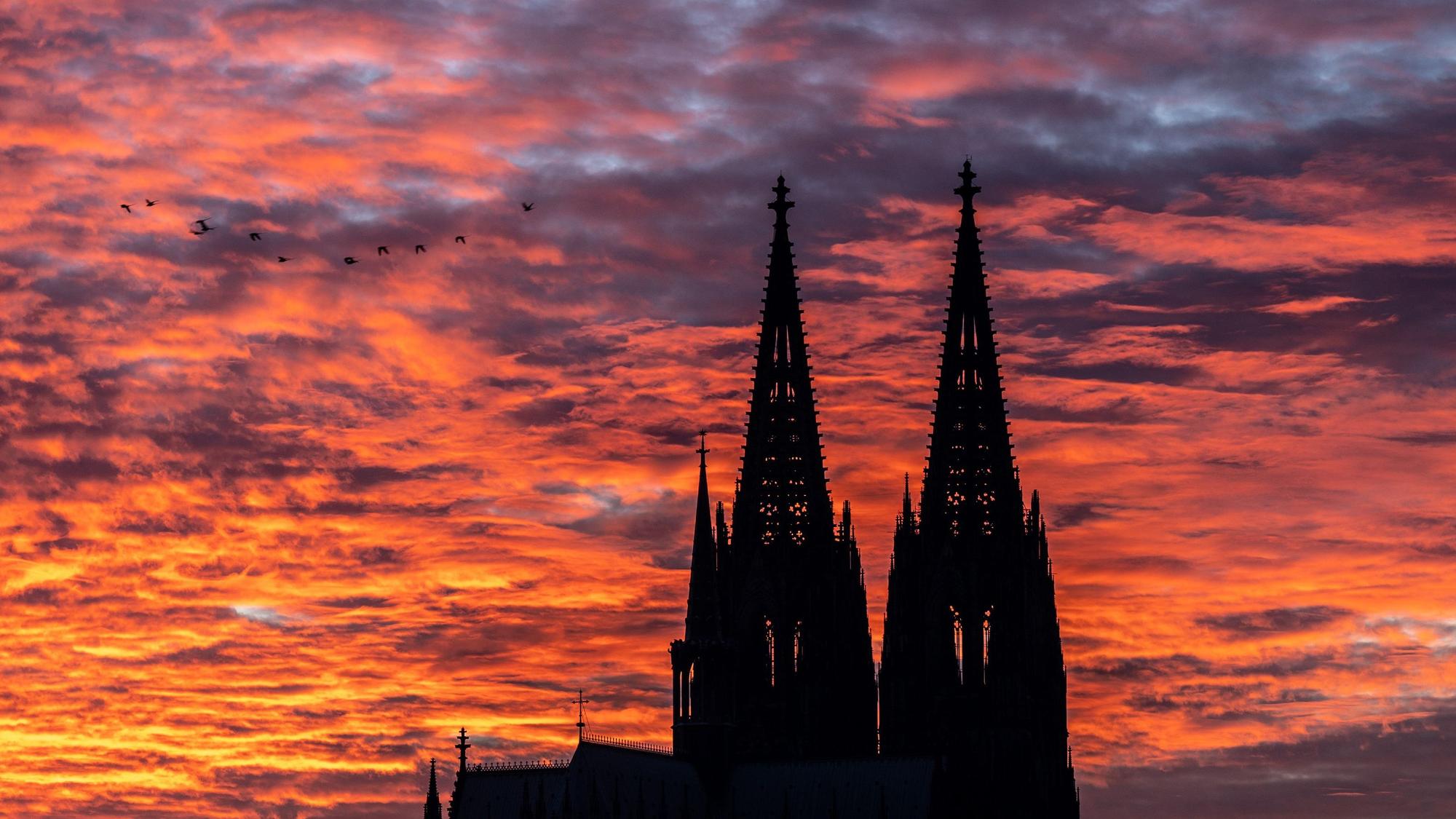 Die Silhouette des Kölner Doms vor einem Sonnenuntergang. Der Himmel ist rot und orange gefärbt. (Symbolbild)