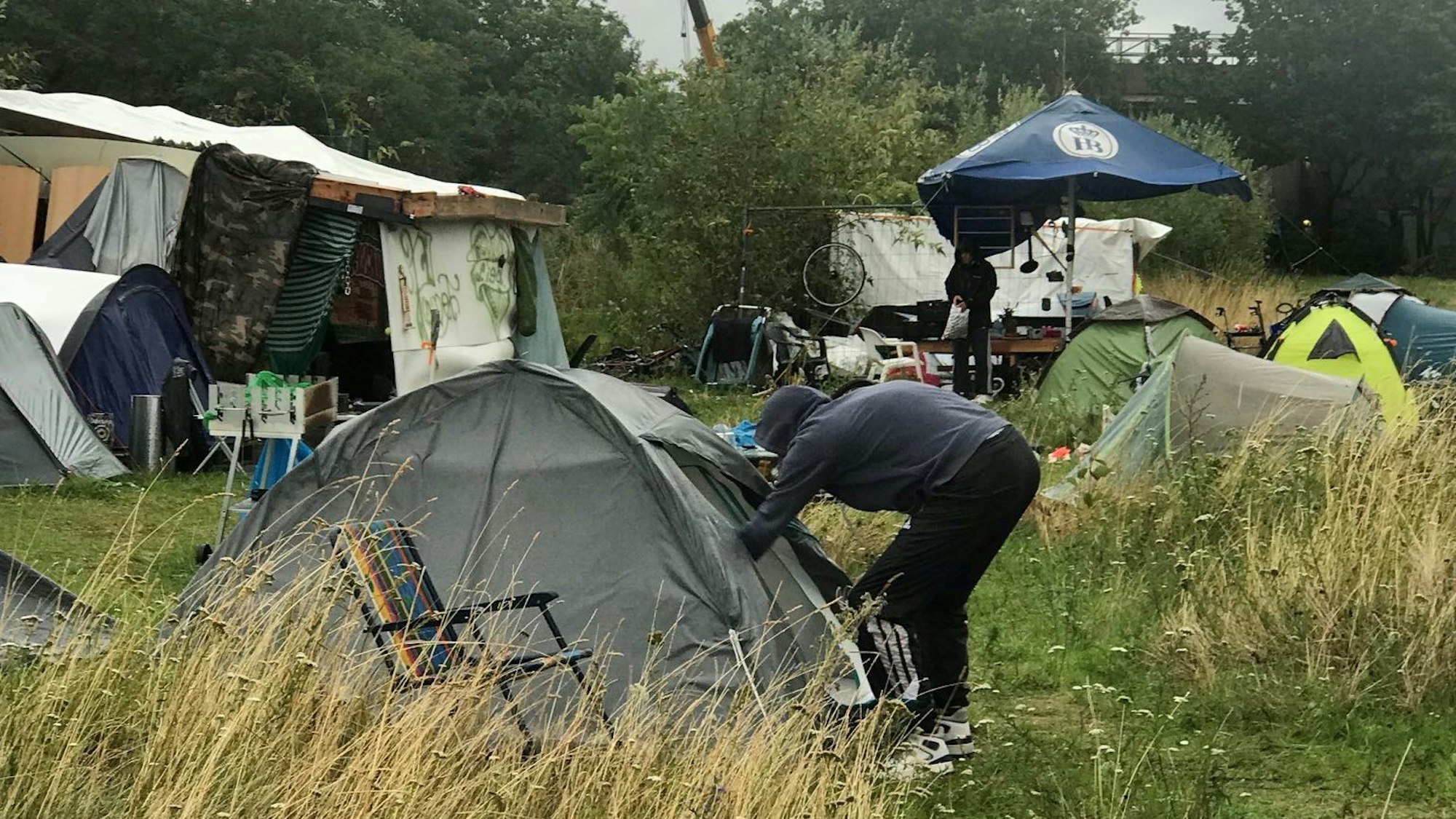 Ein Mann steht vor einem Zelt auf einer Wiese an der Luxemburger Straße