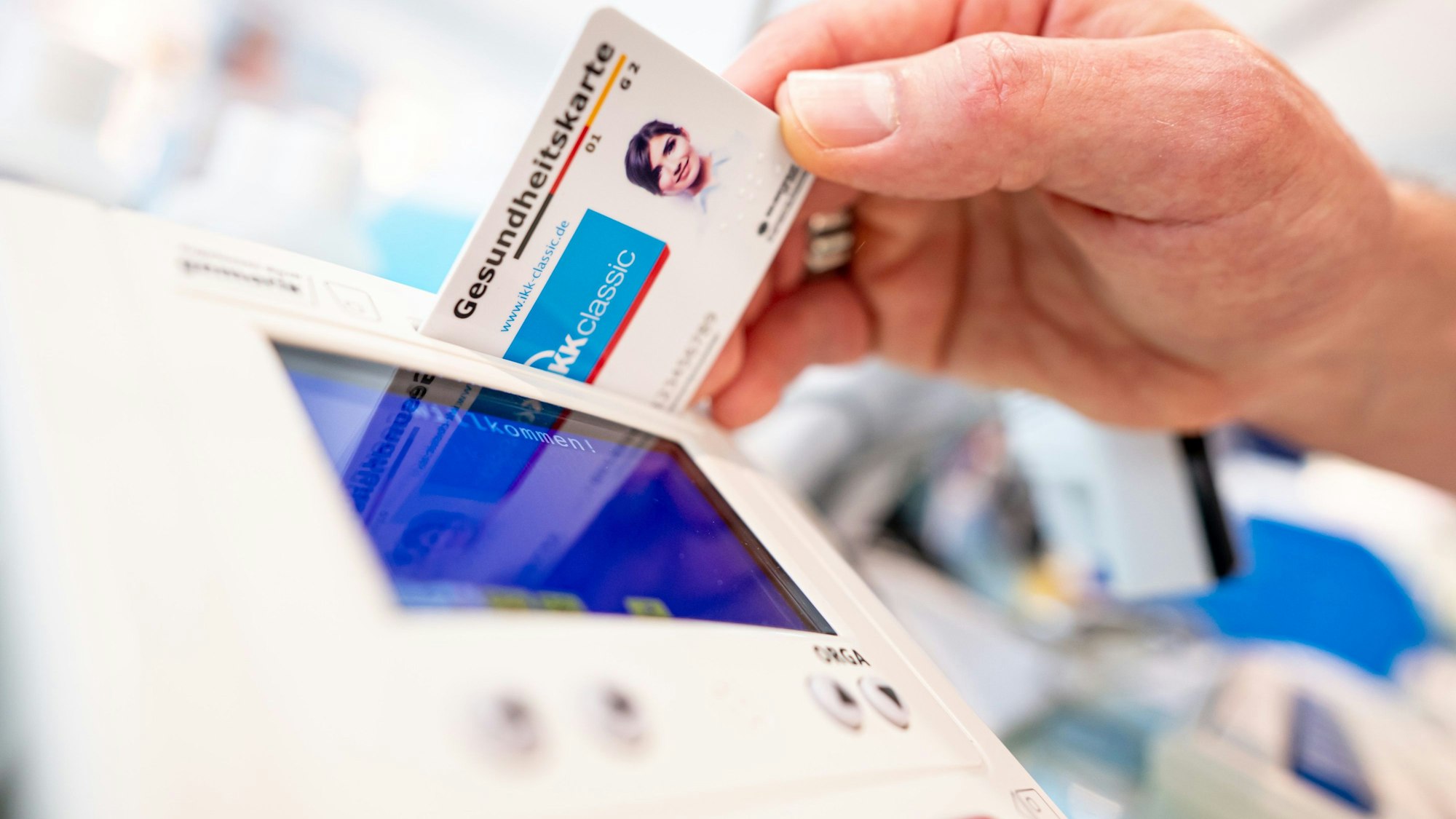 Ein Mitarbeiter einer Apotheke steckt eine Gesundheitskarte in ein Lesegerät.