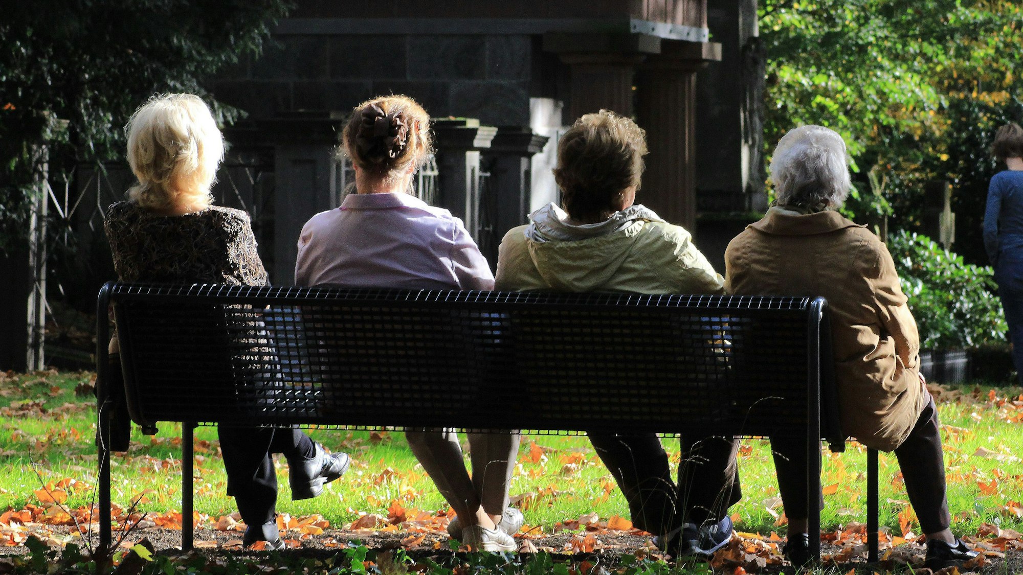 Frauen sitzen auf einer Bank auf dem Friedhof.