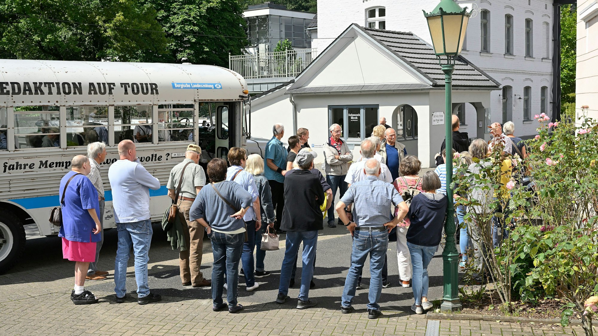 Menschen stehen neben einem historischen Bus in einem historischen Industriegelände.
