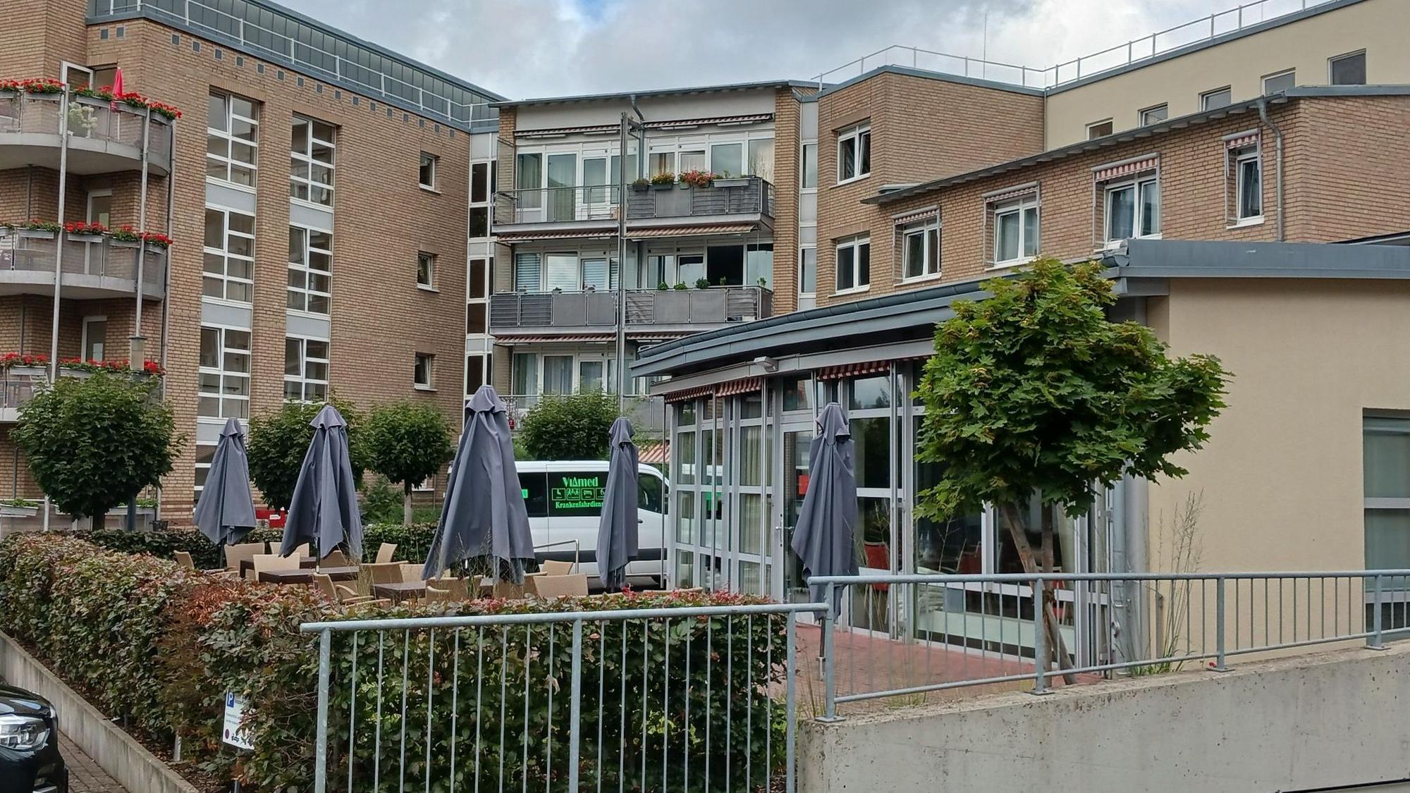 Seniorenzentrum Am Hohen Ufer in Siegburg: ein mehrstöckiges Gebäude mit Balkonen und Sonnenschirmen vor dem Eingang.