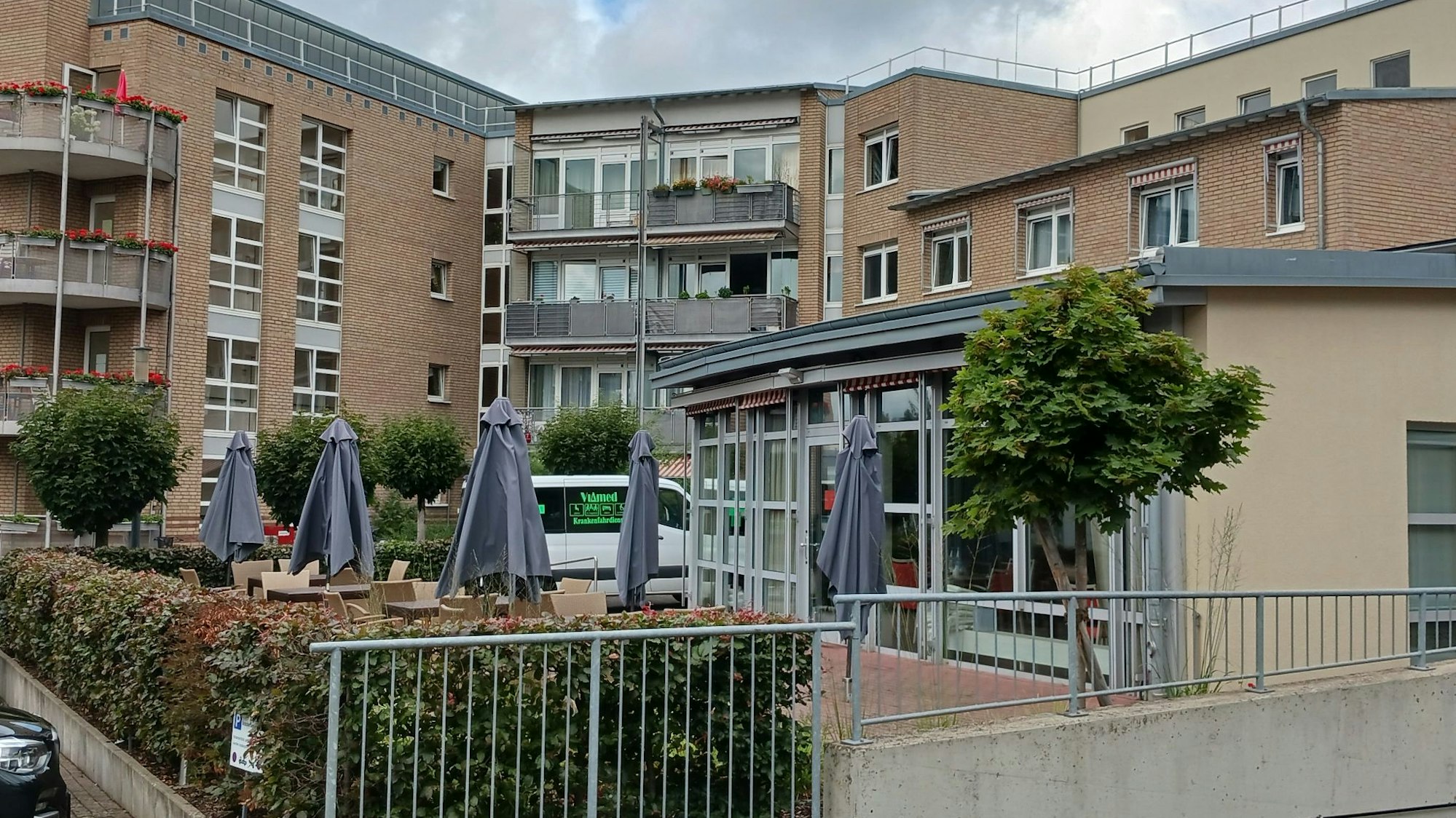 Seniorenzentrum Am Hohen Ufer in Siegburg: ein mehrstöckiges Gebäude mit Balkonen und Sonnenschirmen vor dem Eingang.