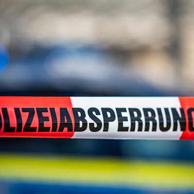 Ein Absperrband mit der Aufschrift «Polizeiabsperrung» ist vor einem Polizeiwagen aufgespannt.