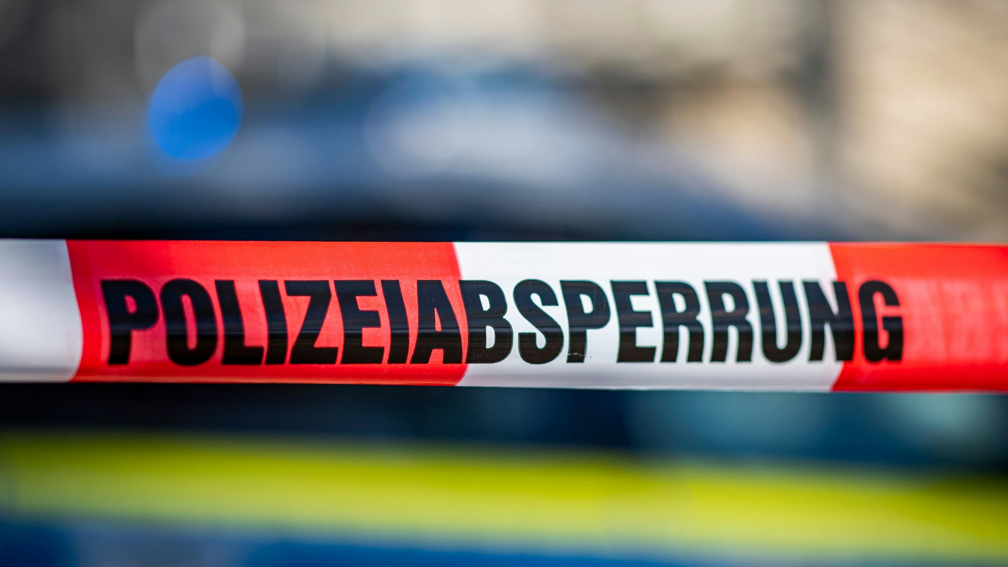 Ein Absperrband mit der Aufschrift «Polizeiabsperrung» ist vor einem Polizeiwagen aufgespannt.
