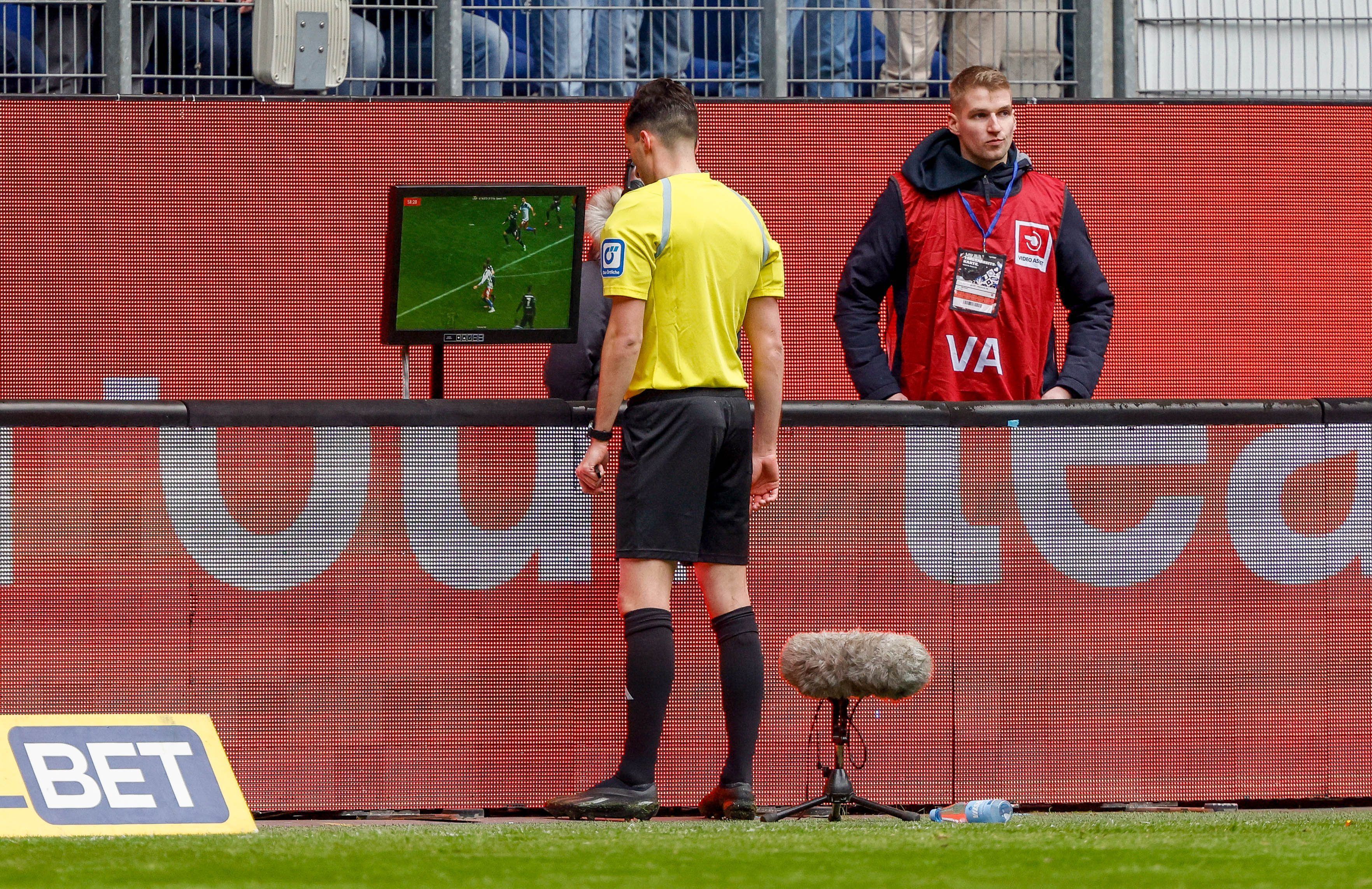 Schiedsrichter Florian Badstuber schaut sich nach dem Anruf des VAR eine Spielszene auf dem Bildschirm an.