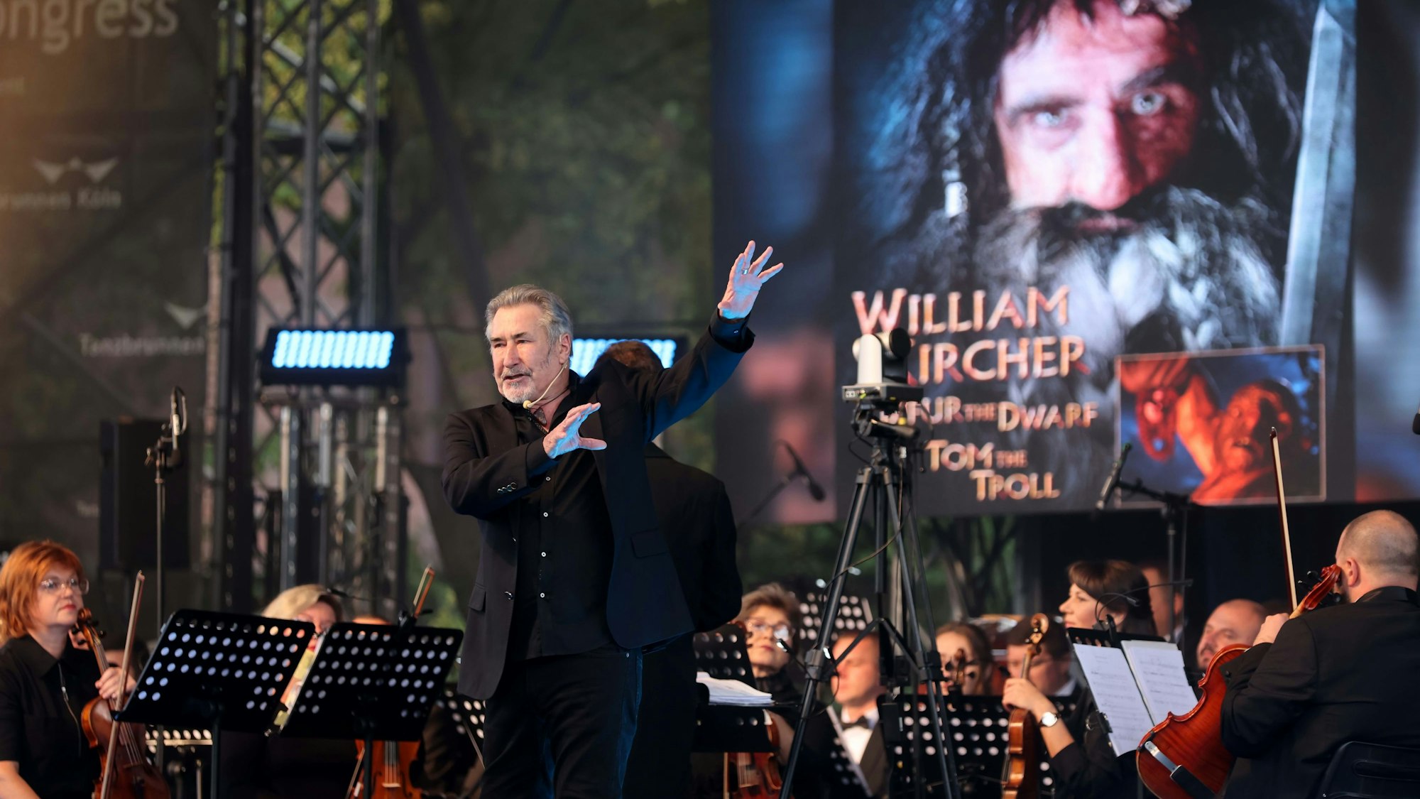 Schauspieler William Kircher und Orchester auf der Bühne im Kölner Tanzbrunnen.