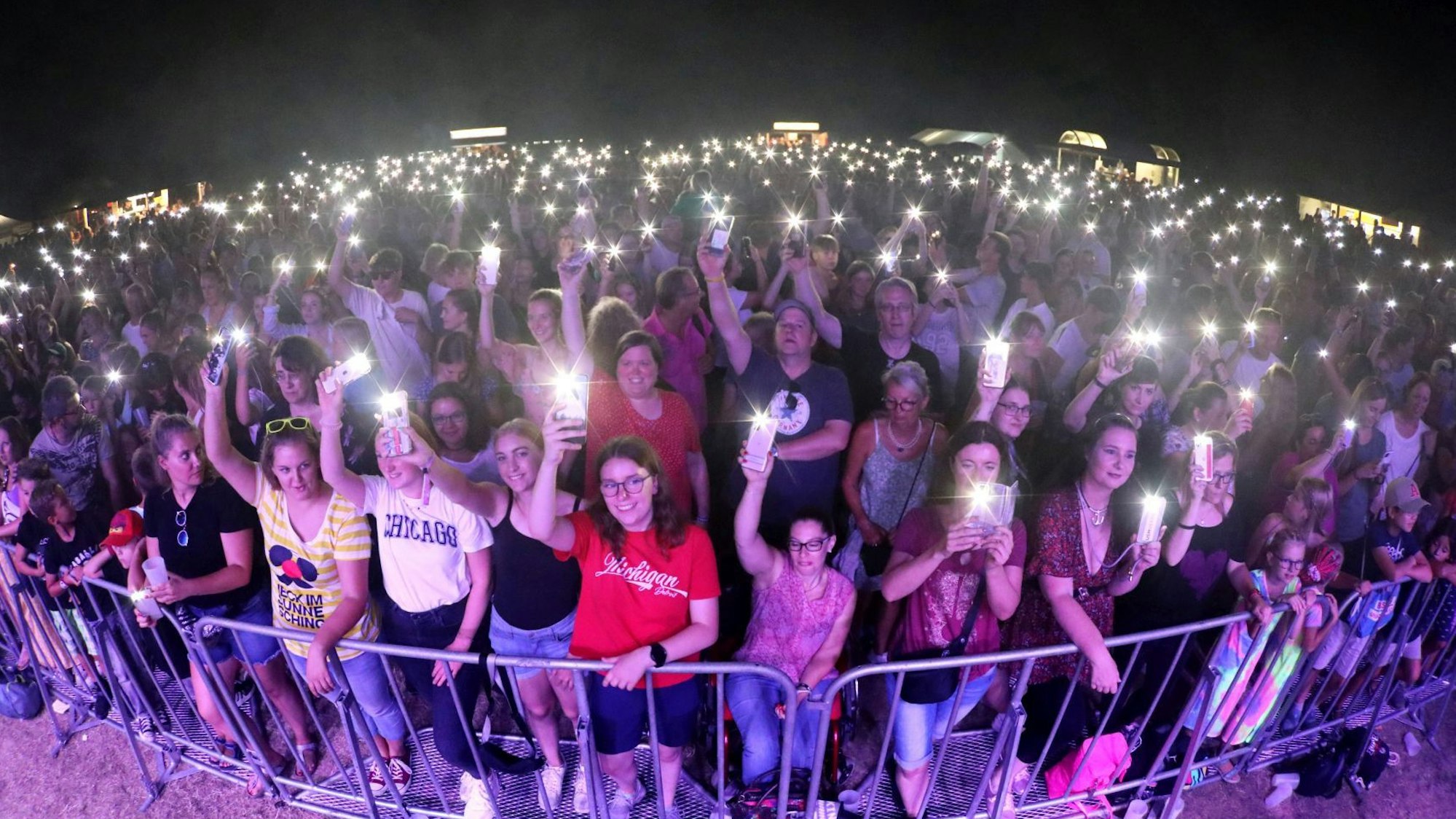 Hunderte, zumeist junge Menschen vor einer Bühne, viele leuchten mit ihren Handy.