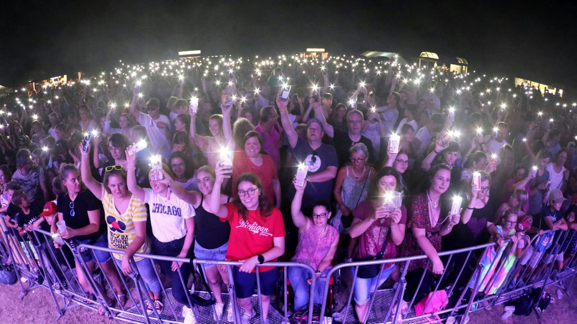 Hunderte, zumeist junge Menschen vor einer Bühne, viele leuchten mit ihren Handy.