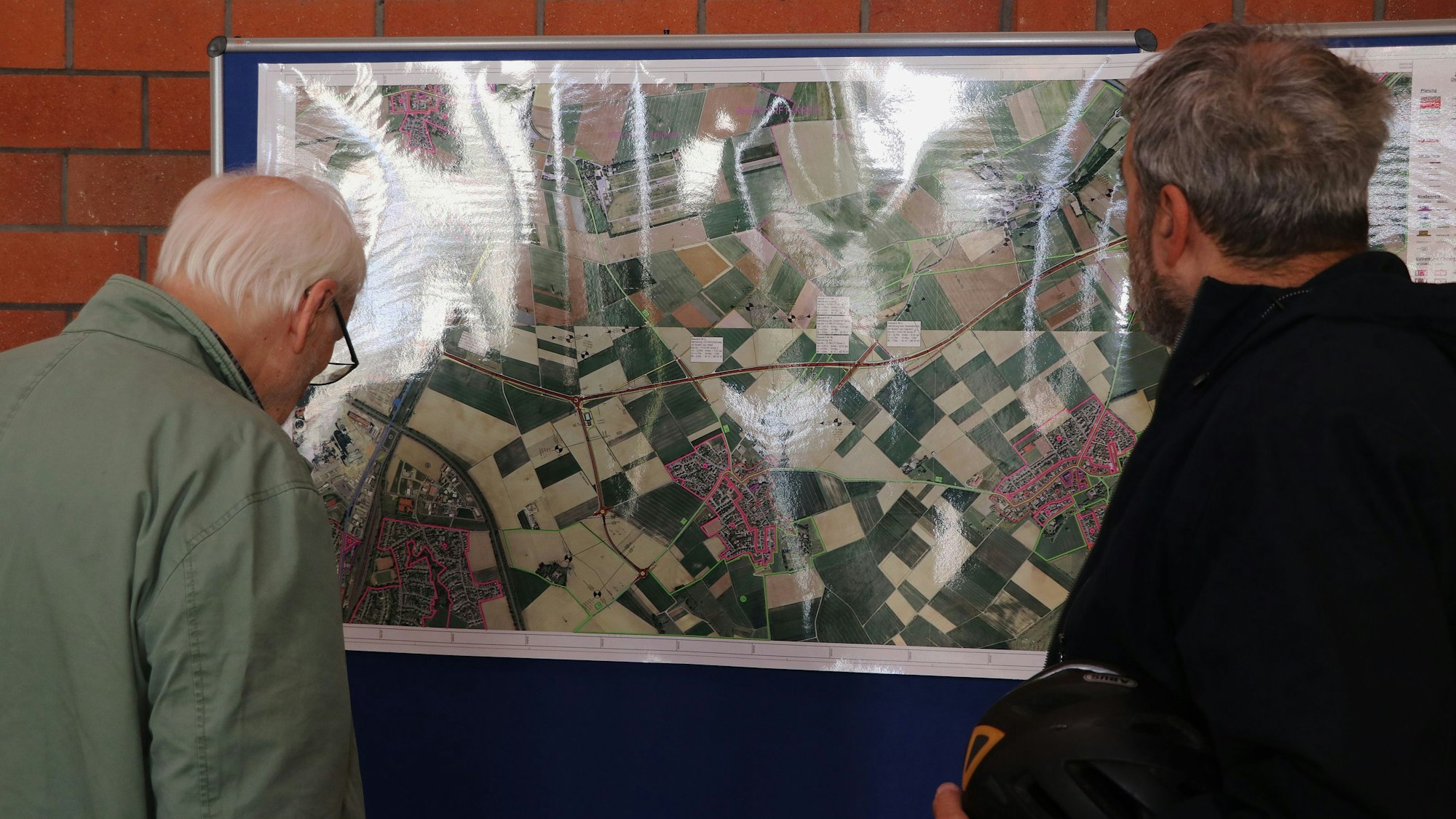 Zwei Männer schauen sich eine Karte an, auf der die geplante Landesstraße eingezeichnet.