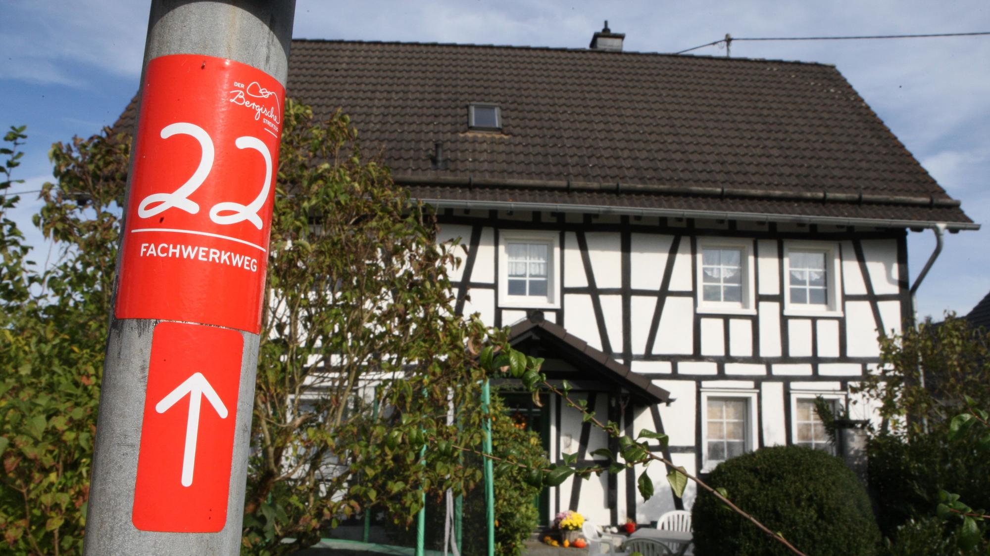Ein Aufkleber mit dem Hinweis auf den Fachwerkweg, im Hintergrund ist ein Fachwerkhaus zu sehen.