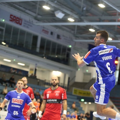 Zu sehen ist ein Handballspieler, der mit Ball hochspringt.