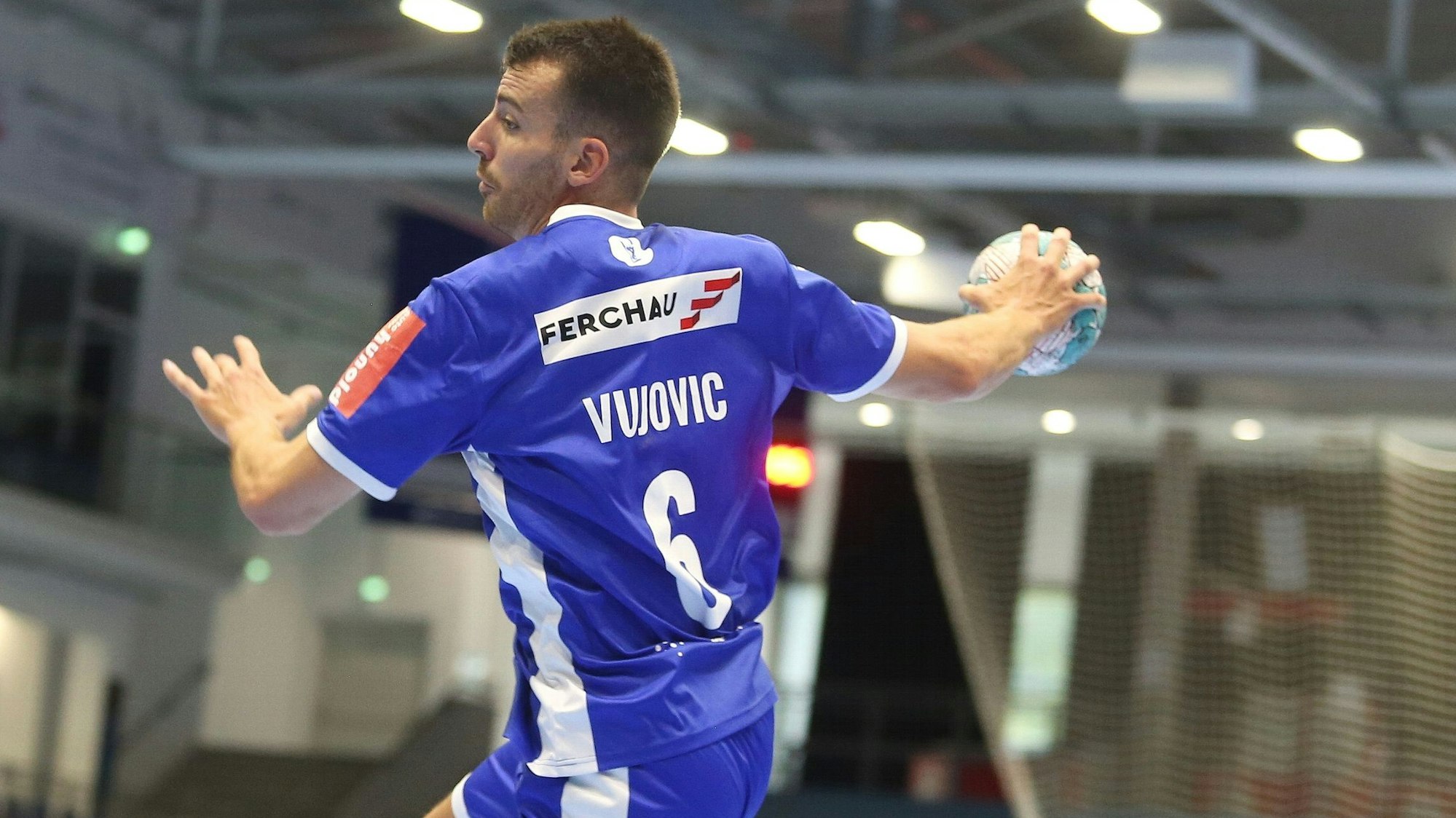 Zu sehen ist ein Handballspieler, der mit Ball hochspringt.