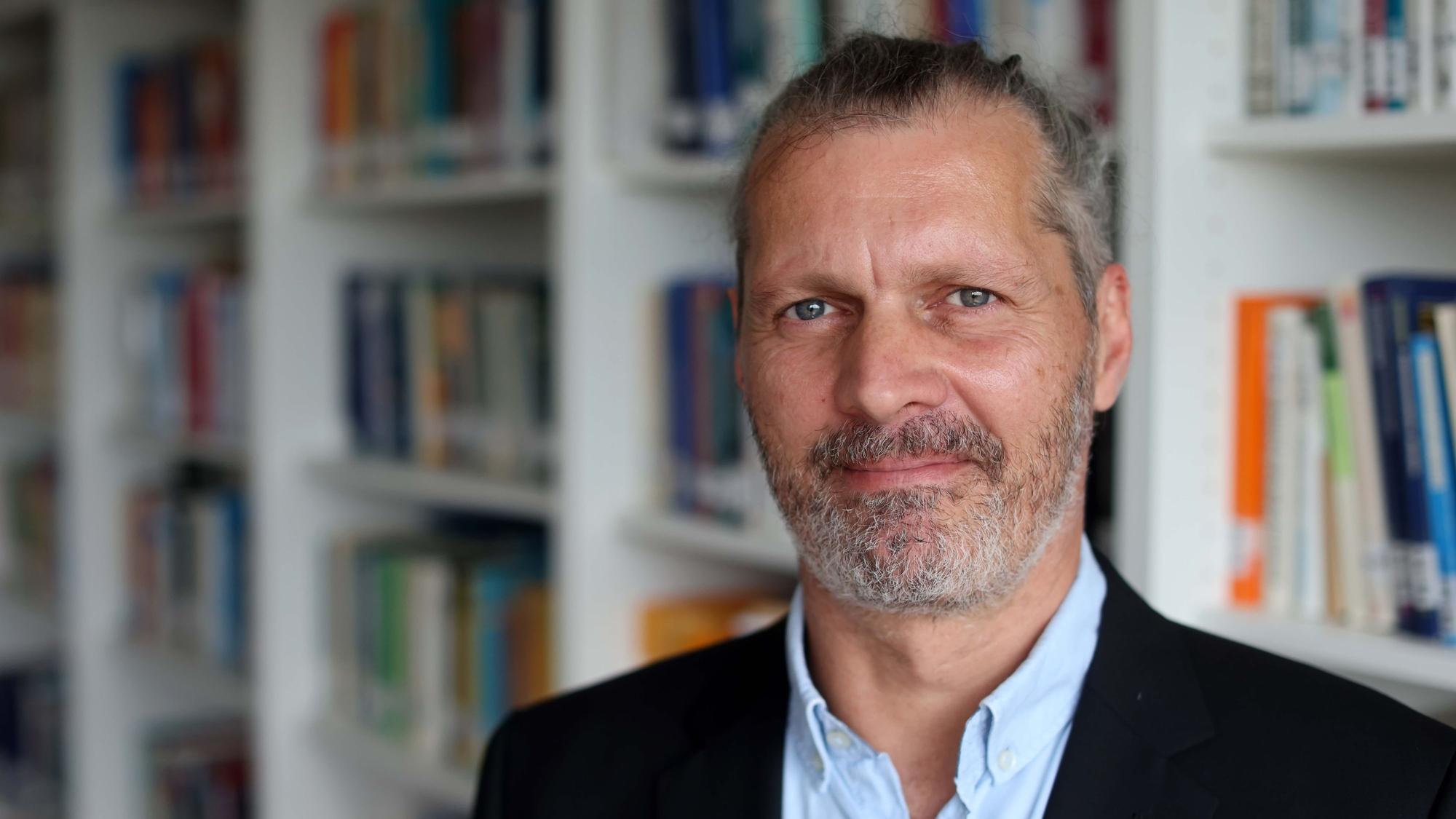 Alexander Niecke steht vor einer Bücherwand