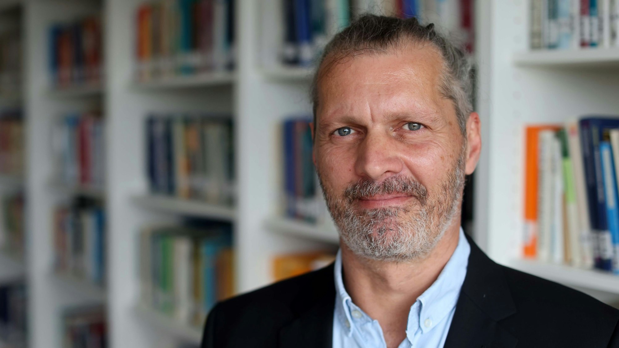 Alexander Niecke steht vor einer Bücherwand