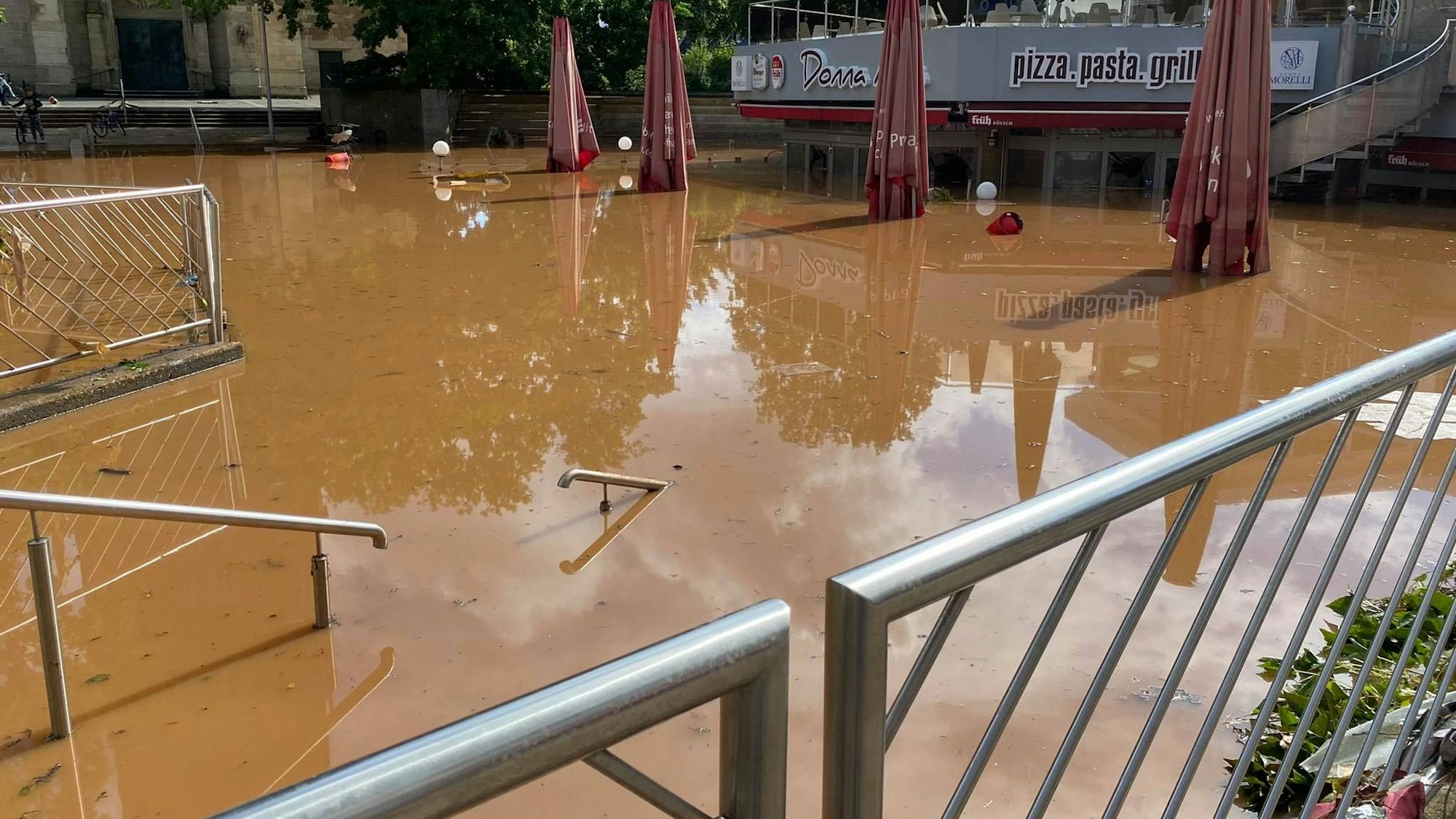 Das Bild zeigt den Herz-Jesu-Vorplatz nach der Flut. Das braune Wasser ist noch nicht abgeflossen.