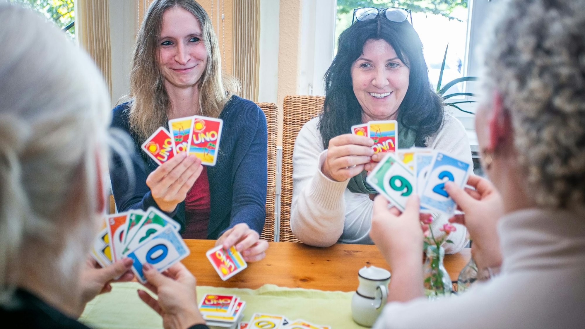 Im Psychosozialen Zentrum in Waldbröl sitzen die Gruppenleiterinnen Sarah Labisch (links) und Dagmar Titze an einem Tisch und spielen Karten mit psychisch beeinträchtigten Menschen, die einen geschützten Raum für den Austausch und Geselligkeit suchen.