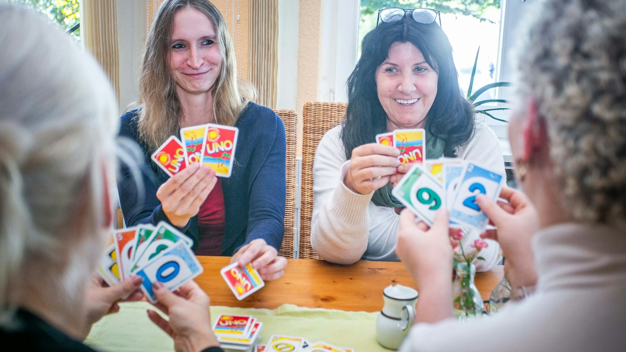 Im Psychosozialen Zentrum in Waldbröl sitzen die Gruppenleiterinnen Sarah Labisch (links) und Dagmar Titze an einem Tisch und spielen Karten mit psychisch beeinträchtigten Menschen, die einen geschützten Raum für den Austausch und Geselligkeit suchen.