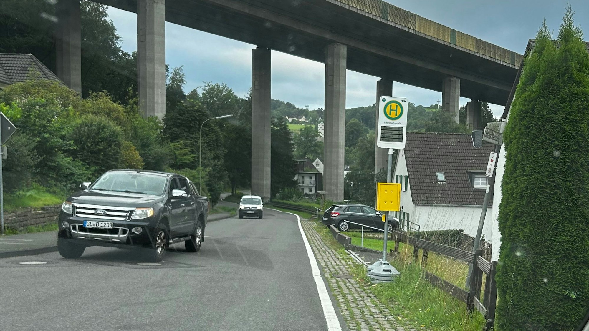 An einer Straße unter einer Autobahnbrücke steht eine Nothaltestelle.