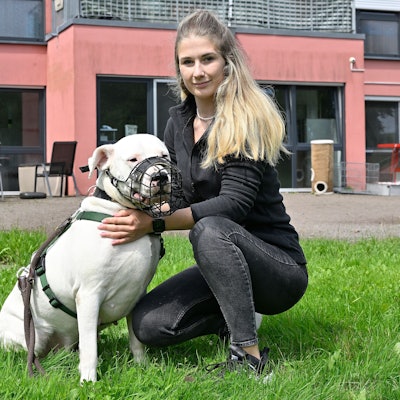 Auf der Wiese vor dem Kürtener Tierheim kniet die neue Leiterin Chiara Zimmermann mit dem Dogo Argentino Coco neben sich.