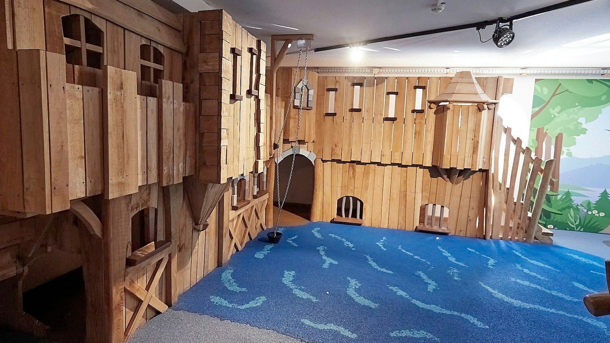 In einem Raum mit Teppich steht eine Holzburg zum Spielen.