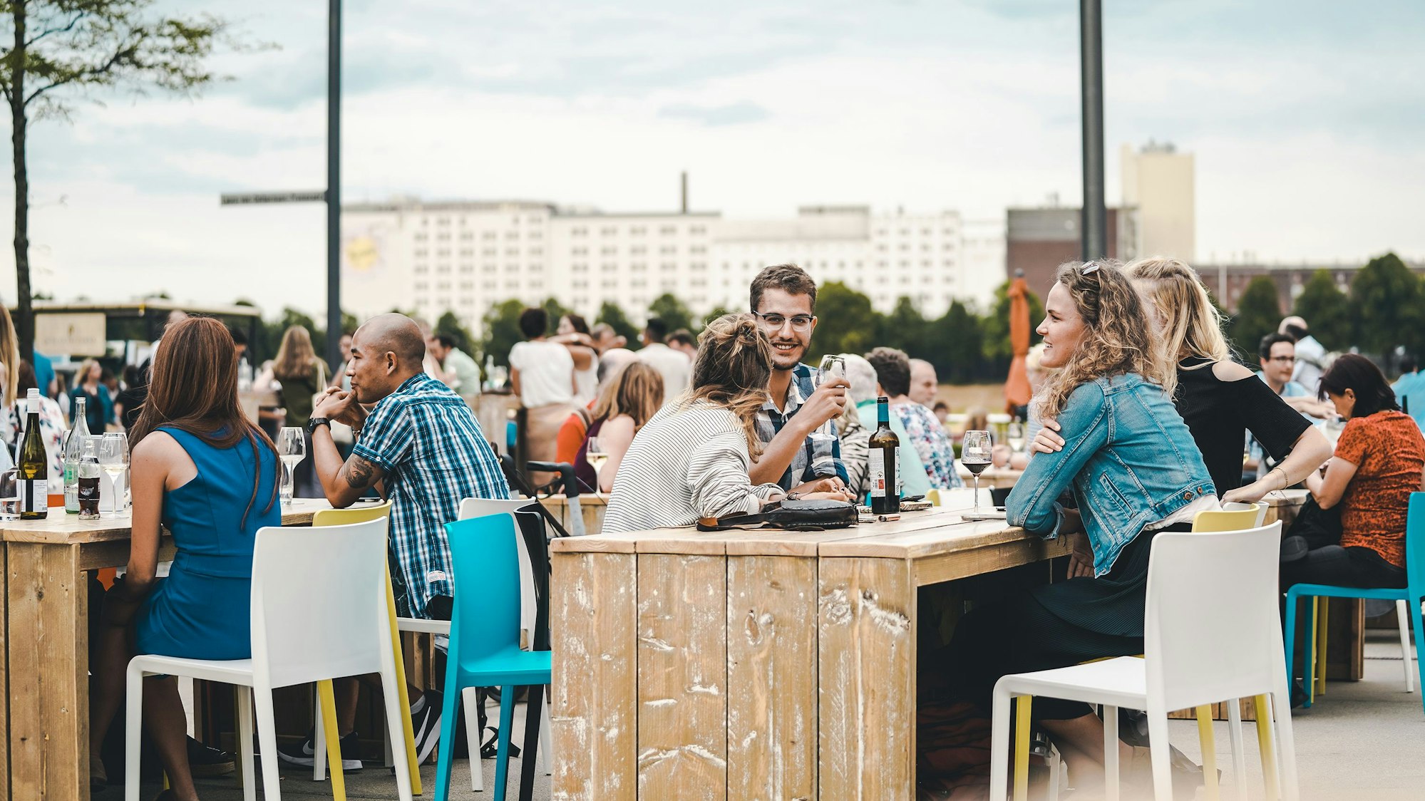 Leute sitzen mit Weingläsern am Rhein.