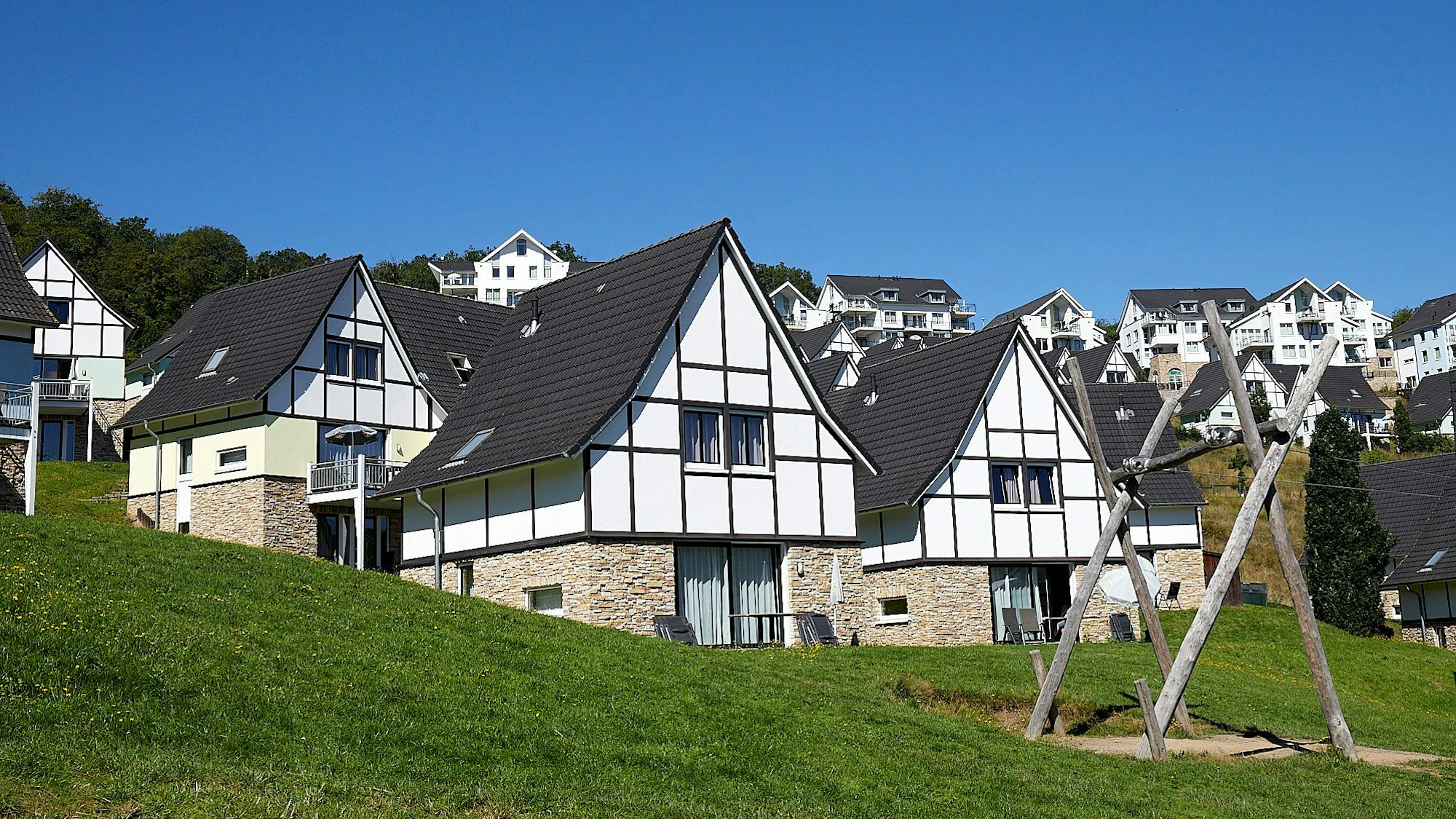 Weiße Fachwerkhäuser des Resort Eifeler Tor stehen an einem Hang.