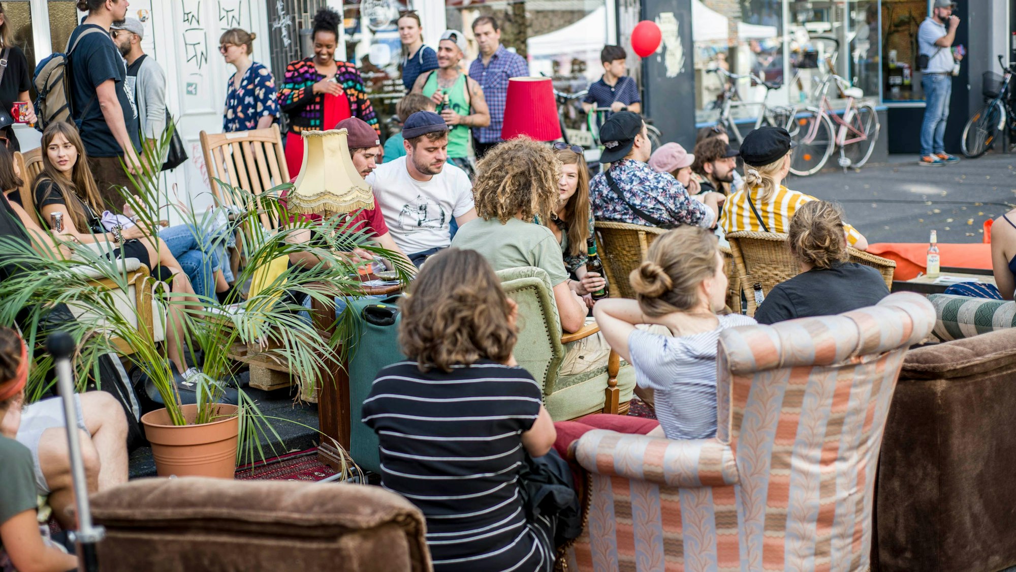 Menschen sitzen in Ehrenfeld in Sesseln auf der Straße.