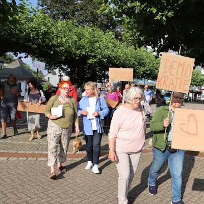 Teilnehmer einer Demonstration halten Schilder mit der Aufschrift „Demokratie“.