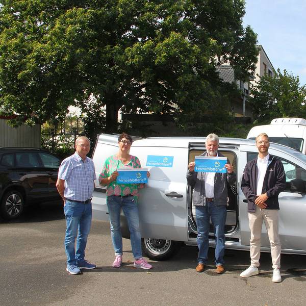 Volker Nüßmann, Manuela Pütz und Hans-Peter Bouhs von der Tafel Mechernich, sowie Nils Detering, Repräsentant der Deutschen Fernsehlotterie, stehen vor einem gespendeten Wagen der Deutschen Fernsehlotterie.