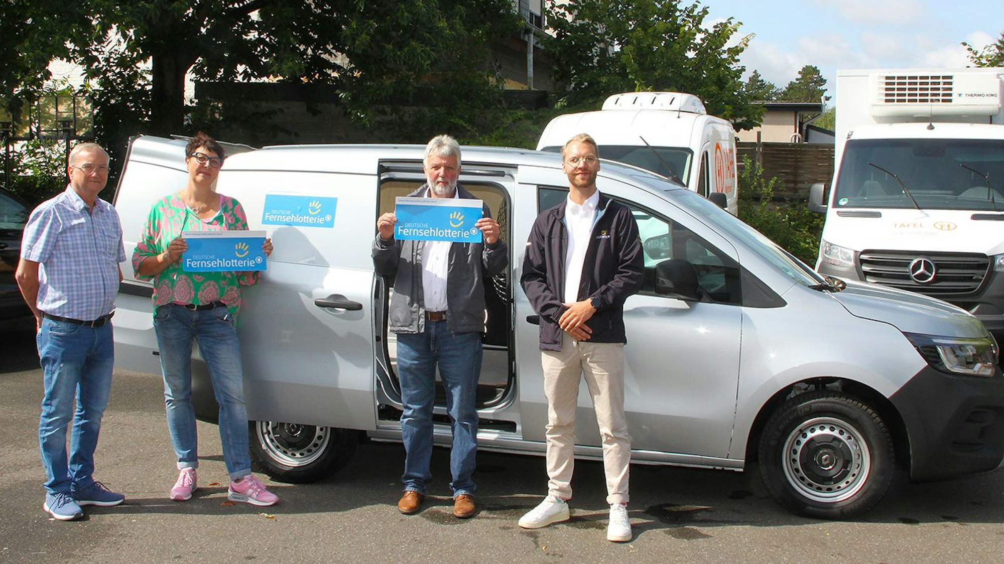 Volker Nüßmann, Manuela Pütz und Hans-Peter Bouhs von der Tafel Mechernich, sowie Nils Detering, Repräsentant der Deutschen Fernsehlotterie, stehen vor einem gespendeten Wagen der Deutschen Fernsehlotterie.