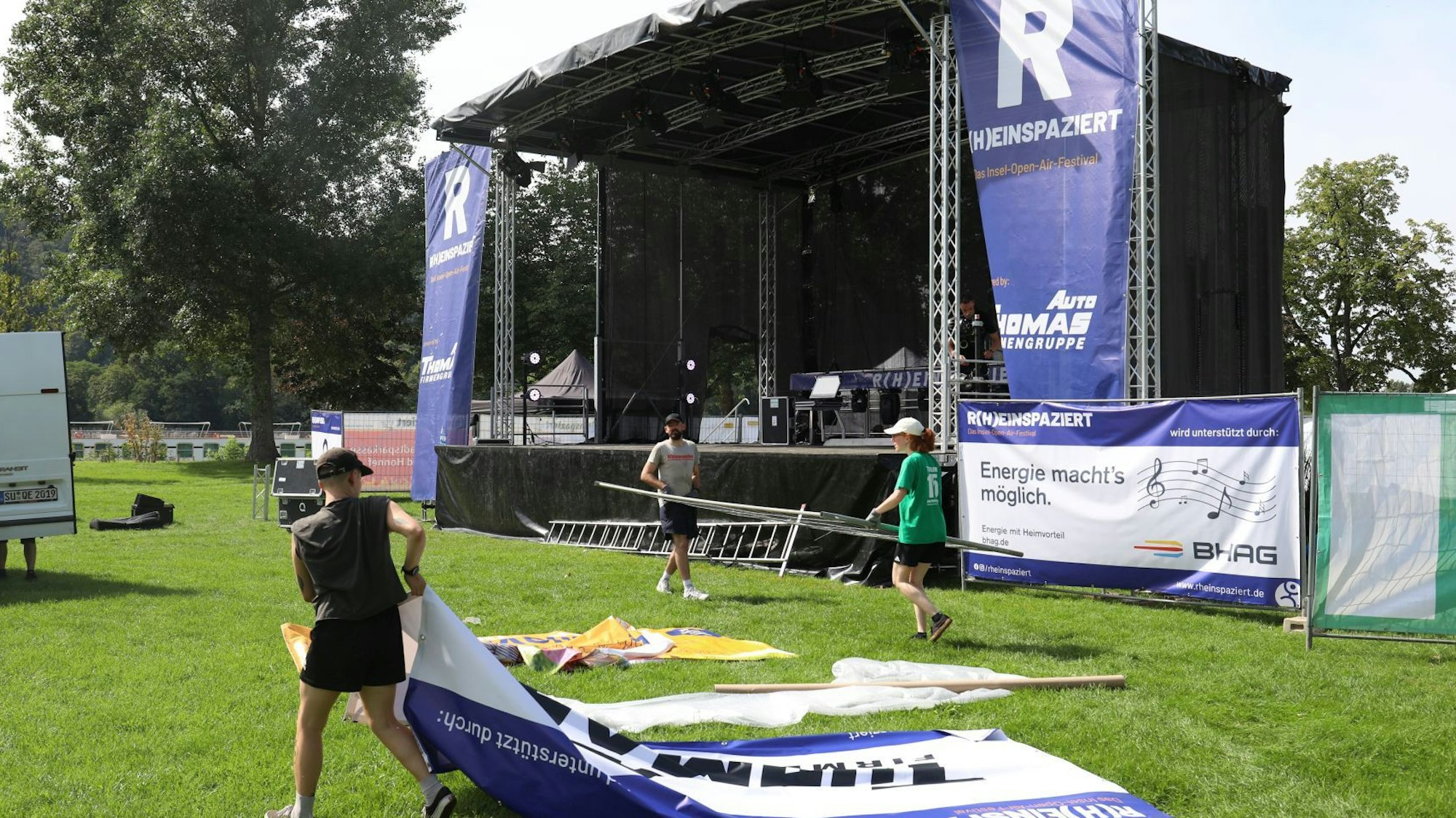 Helfer tragen Banner und Zaunelemente vor einer großen Bühne.