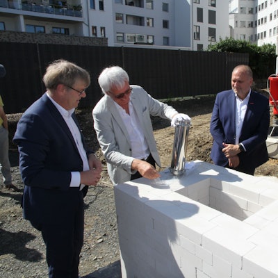 Fünf Männer stehen um ein weißes Mauerwerk für einen Grundstein herum