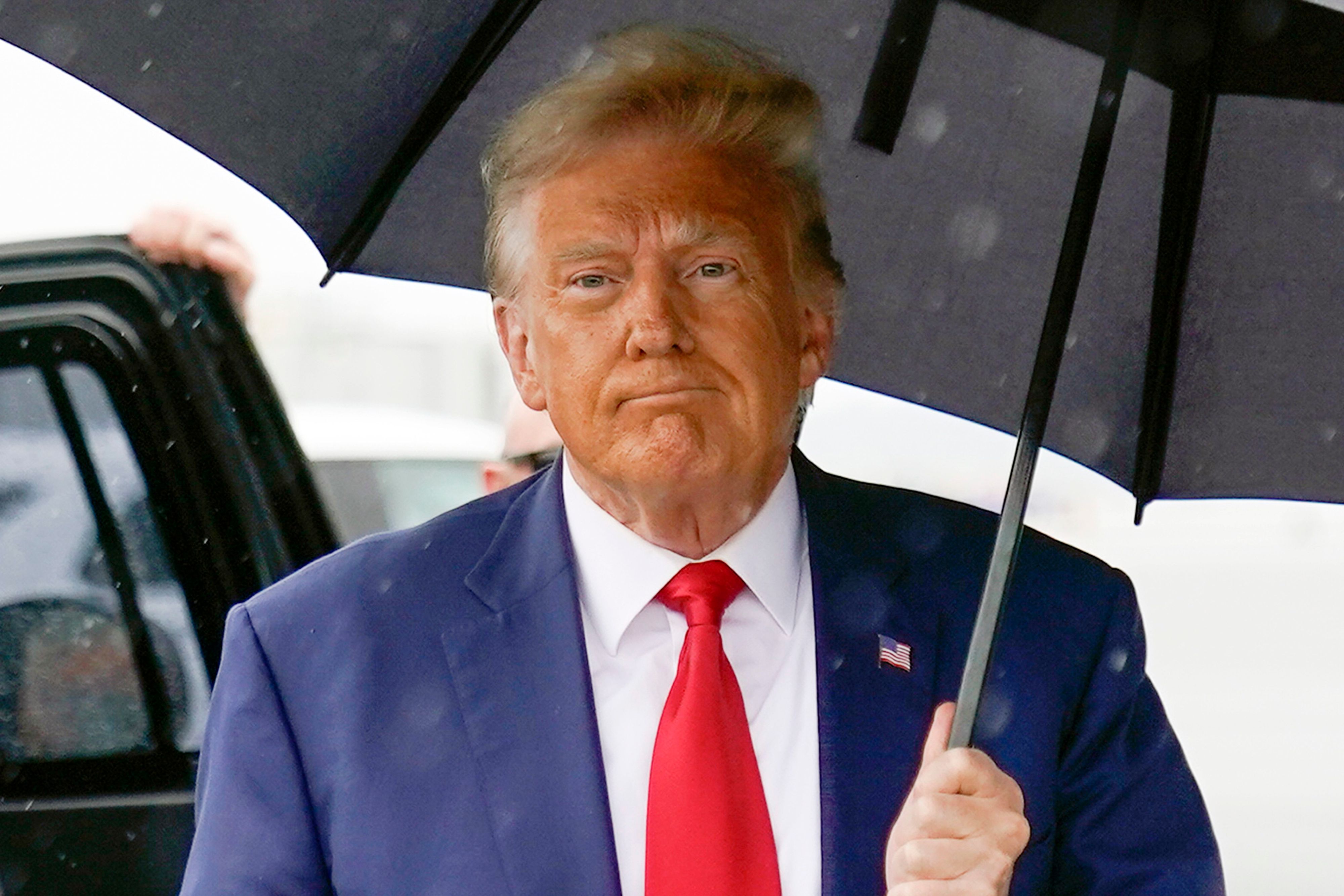 Der Republikaner Donald Trump hält einen Regenschirm.