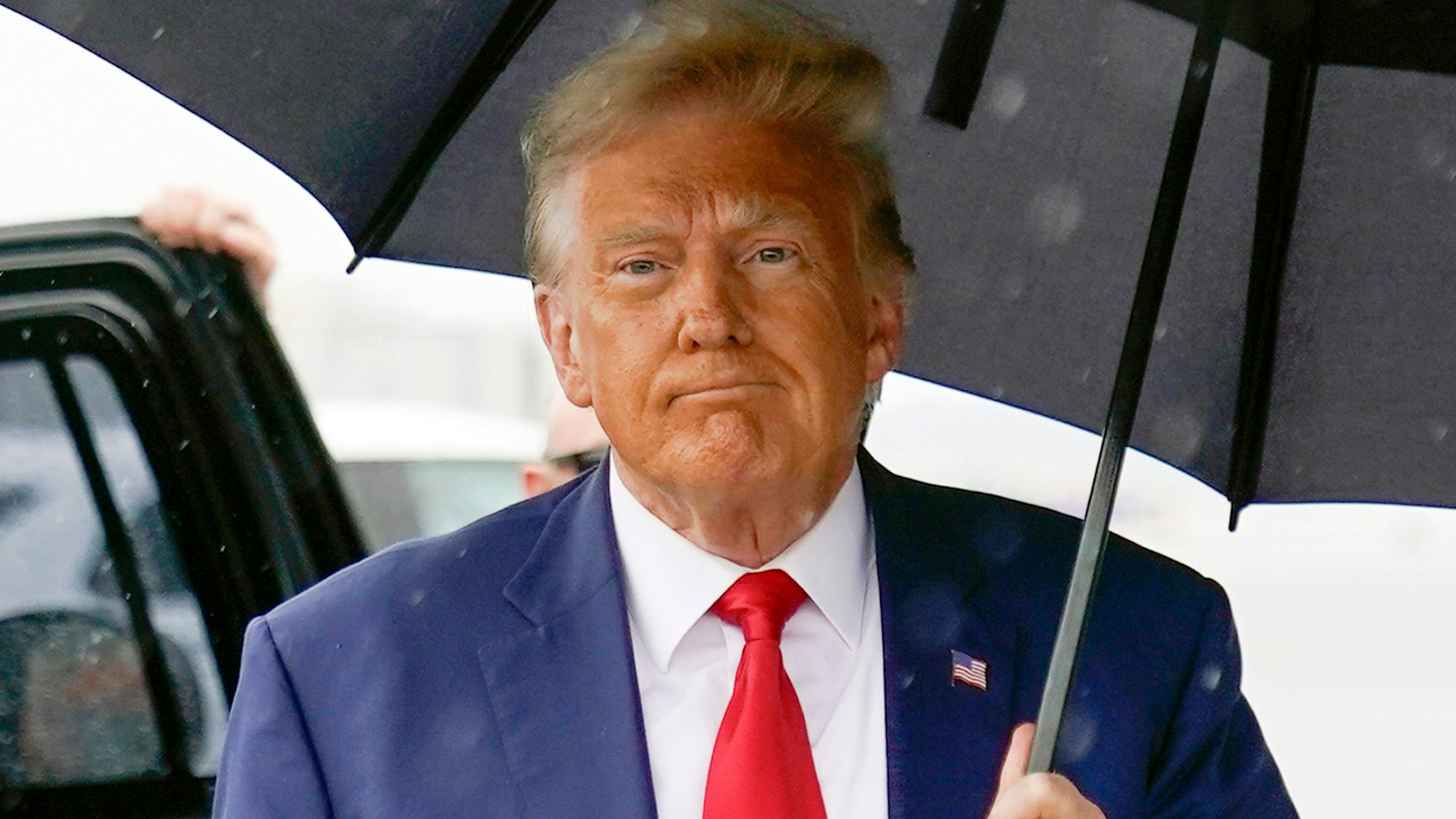 Der Republikaner Donald Trump hält einen Regenschirm.