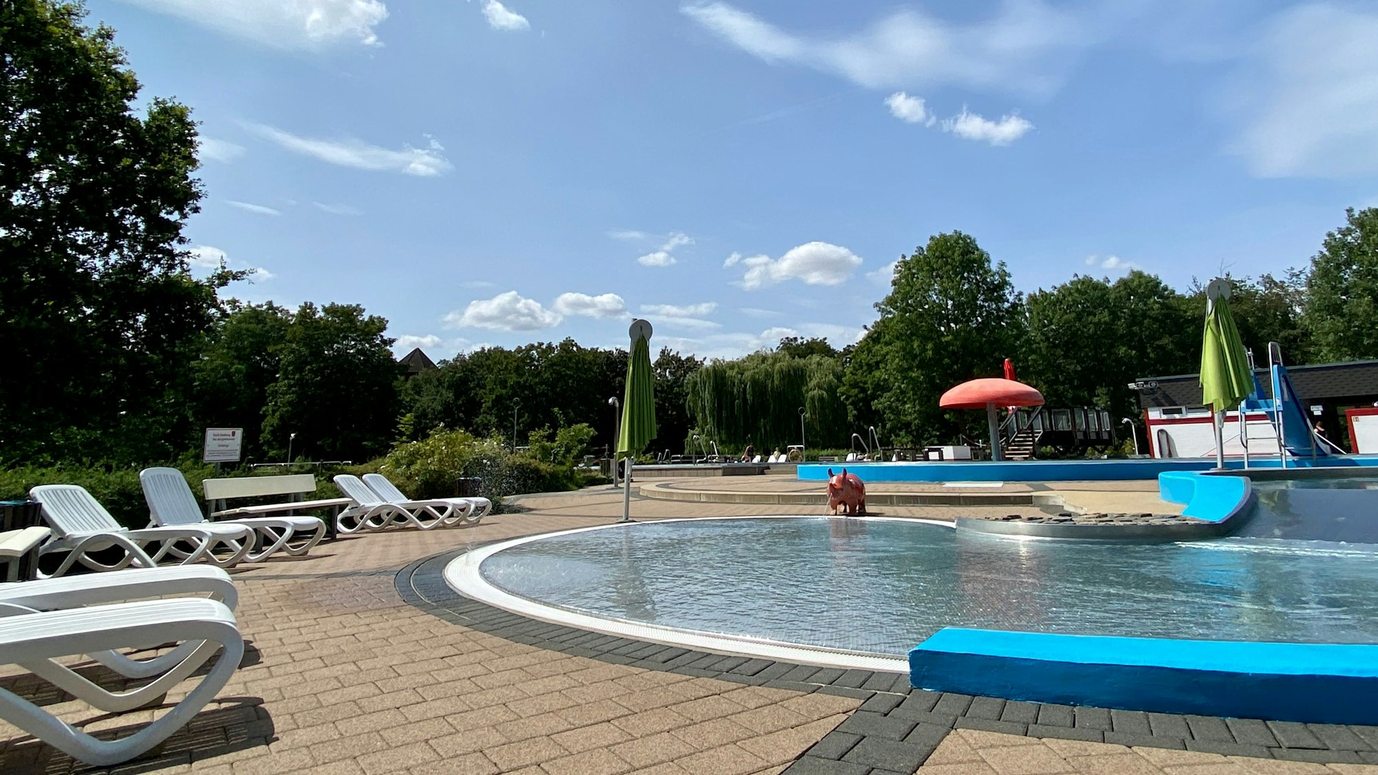 Leere Liegestühle stehen am Rand eines Schwimmbeckens.